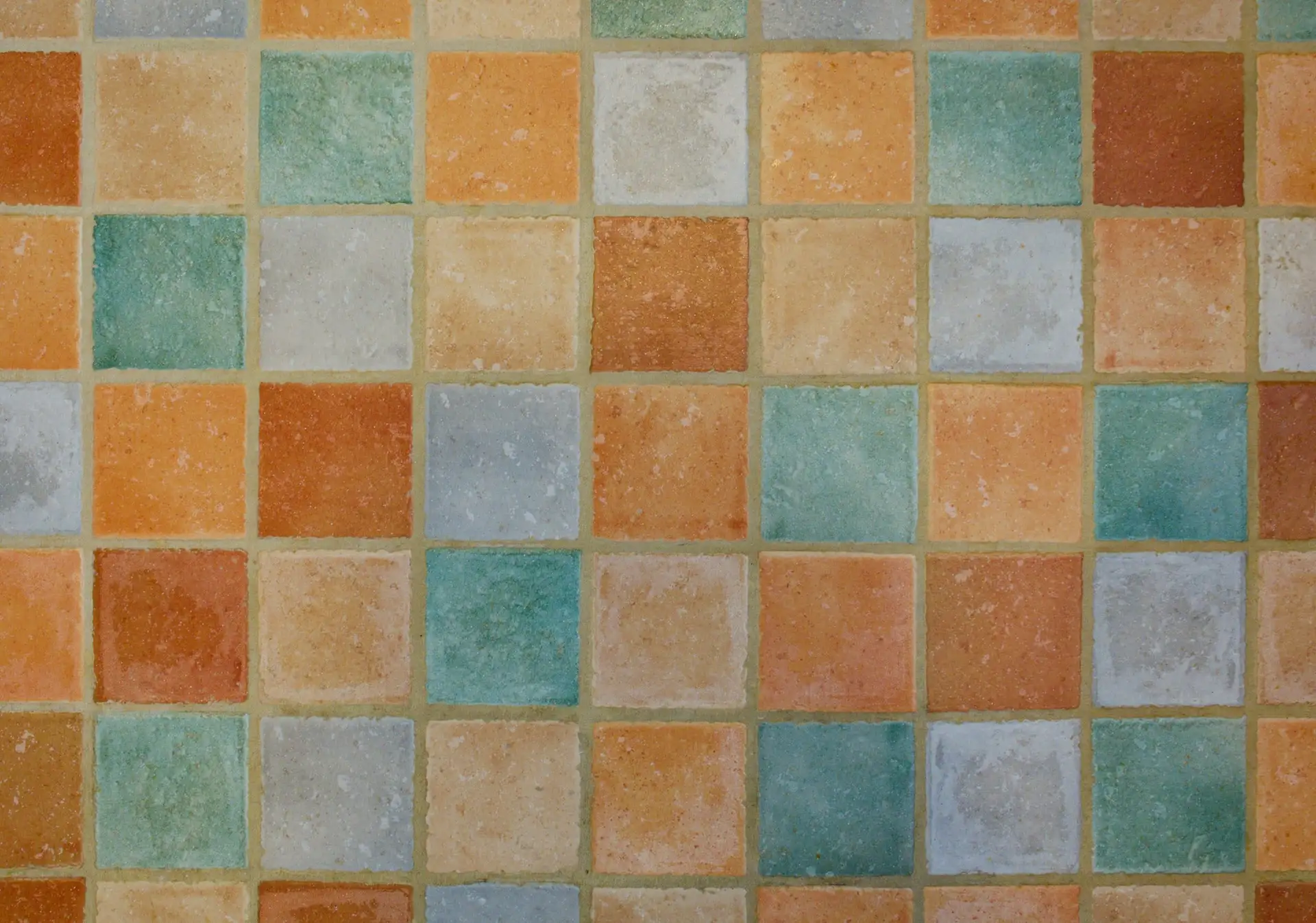 Pared de azulejos cuadrados en tonos tierra, verde y azul