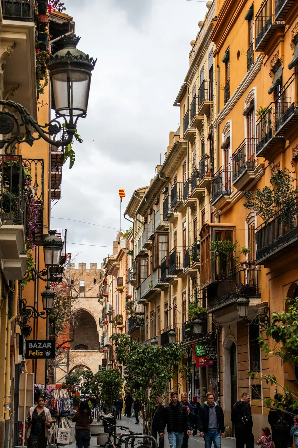 Calle del centro de Valencia con balcones de hierro y las Torres de Quart al fondo